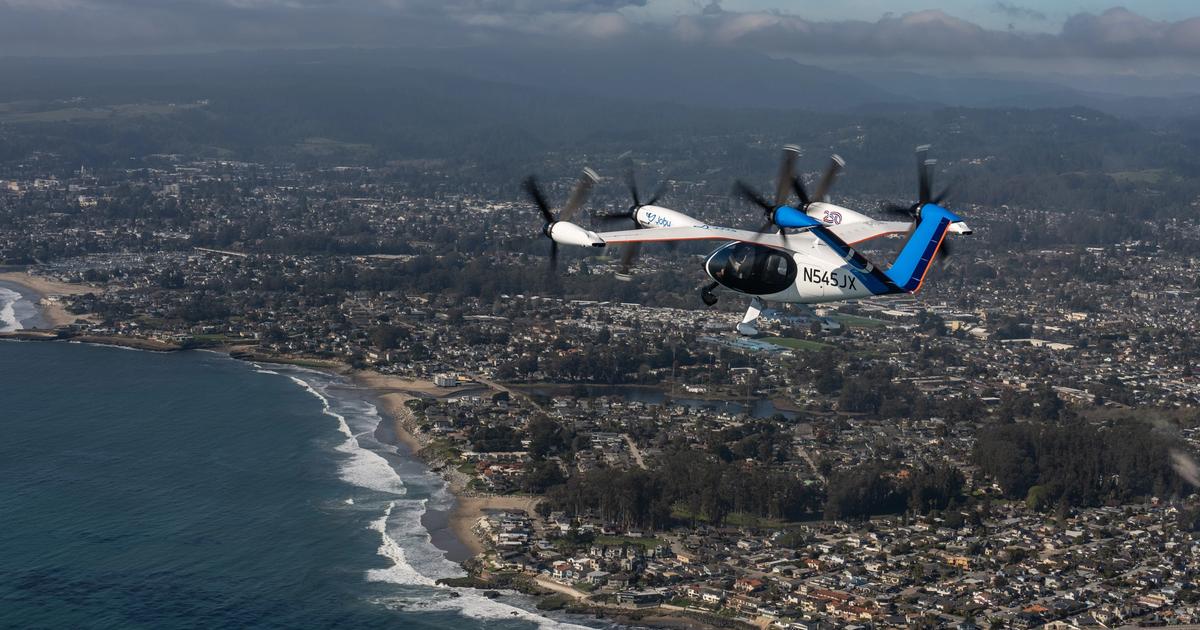 Joby aircraft flying over a coastal city